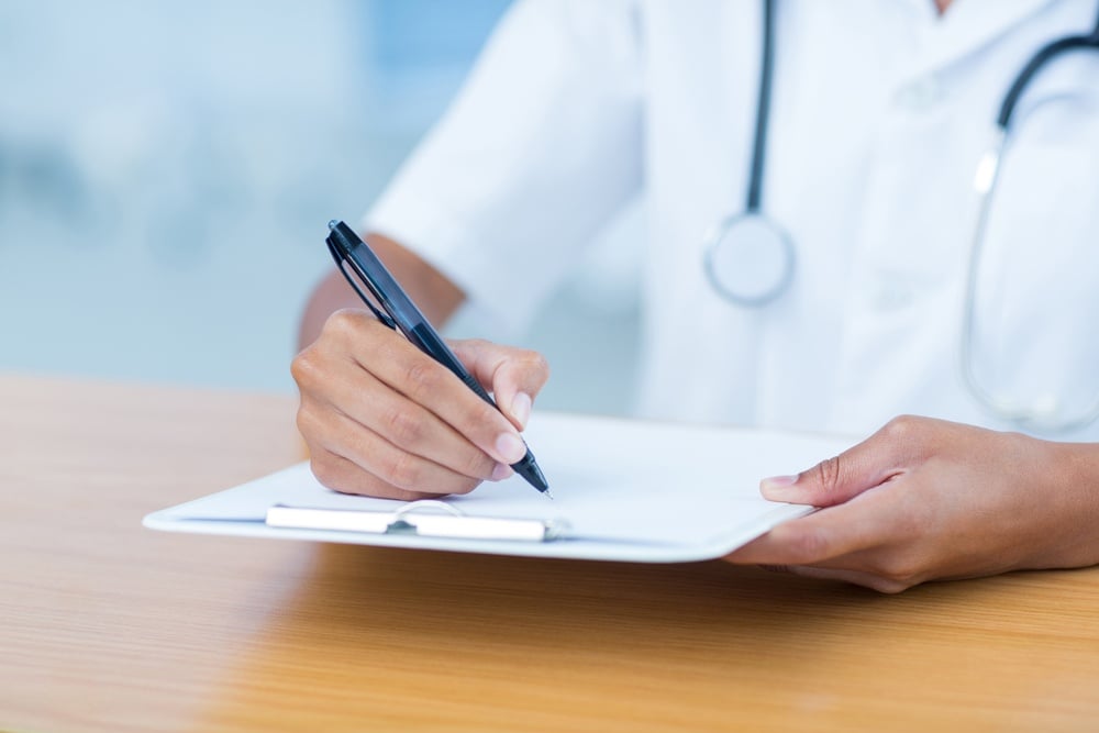 Doctor holding clipboard with file in hospital room